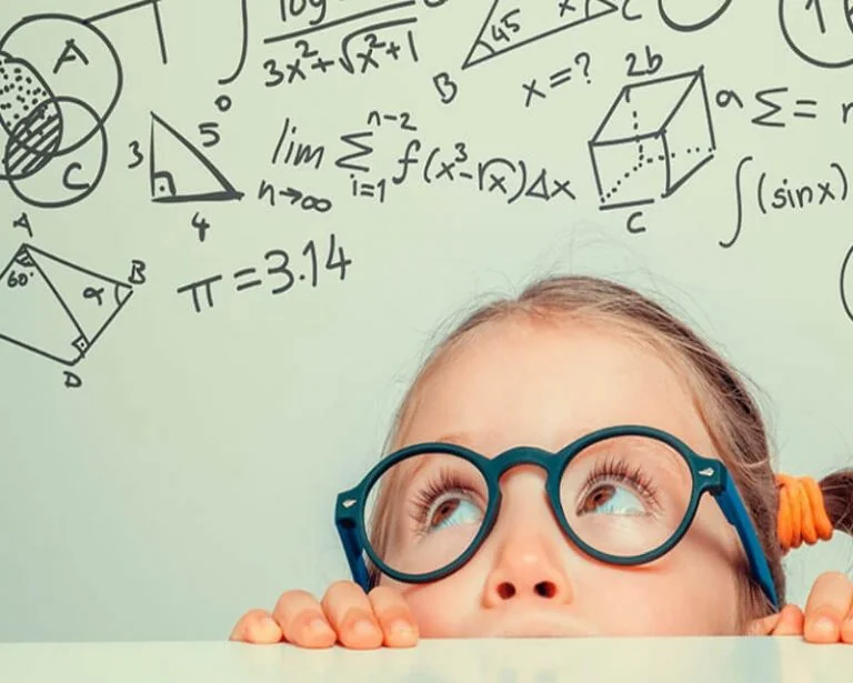 Niña con lentes frente a fórmulas de matemáticas