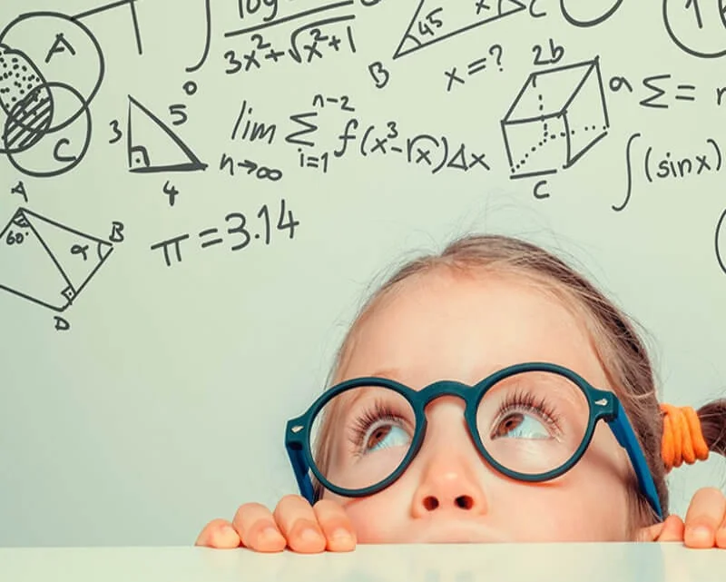 Niña con lentes frente a fórmulas de matemáticas